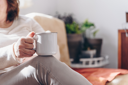 Close up of elderly woman hands while holding a cup of coffeeの写真素材