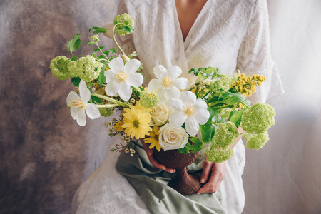 Young woman in a white dress holding vase with flowers. Vintage, romantic concept.の写真素材