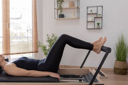 Young woman exercising on pilates reformer bedの写真素材