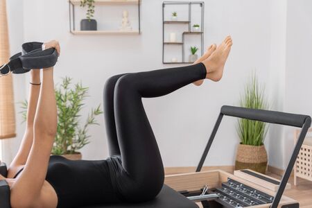 Young woman exercising on pilates reformer bedの写真素材