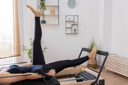 Young woman exercising on pilates reformer bedの写真素材