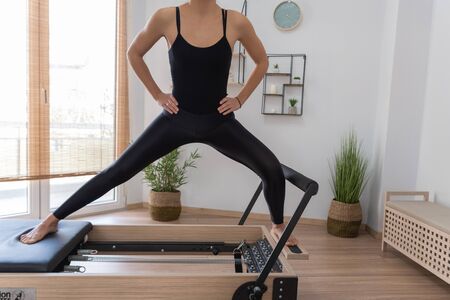 Young woman exercising on pilates reformer bed