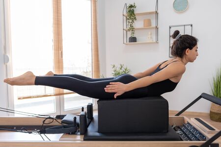 Young woman exercising on pilates reformer bedの写真素材