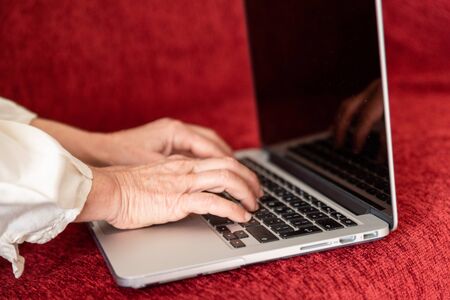 Hands of mature woman using computer at home, top viewの写真素材