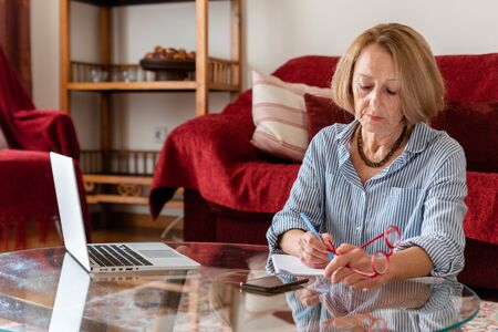 Middle age senior woman working at home using computerの写真素材