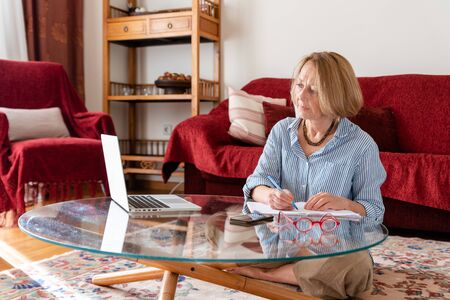 Middle age senior woman working at home using computerの写真素材