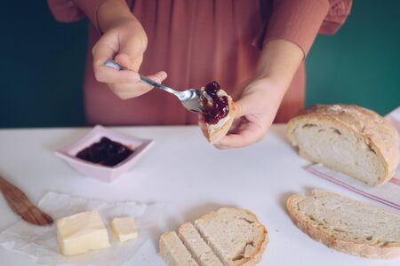 Womans hand spreads jam on homemade breadの写真素材