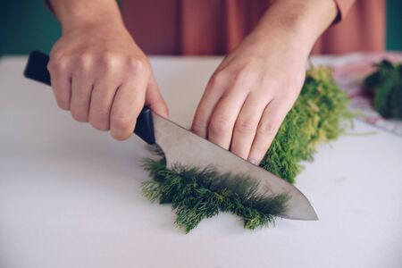 Woman cutting dill on white marble
