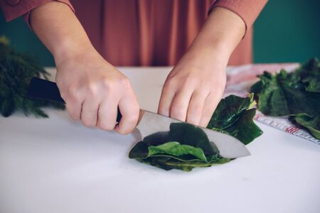 Woman cutting spinach on the marble at her kitchenの写真素材