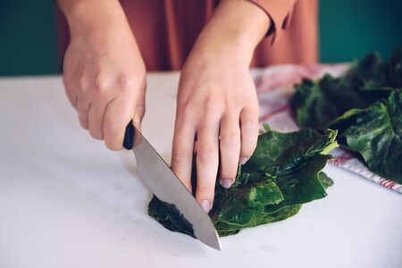 Woman cutting spinach on the marble at her kitchenの写真素材