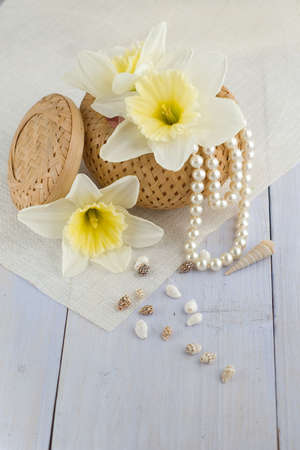  box with pearls, seashells and flowers on light-blue table 	の写真素材
