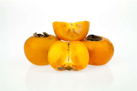 Persimmons, one whole and one cut in two pieces isolated on a white backgroundの写真素材
