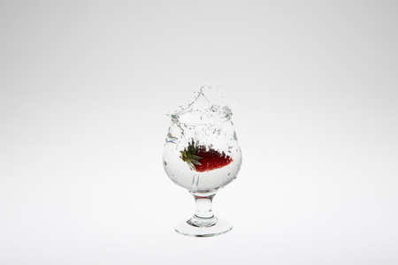 Close-up image of strawberry dropped to water on white backgroundの写真素材