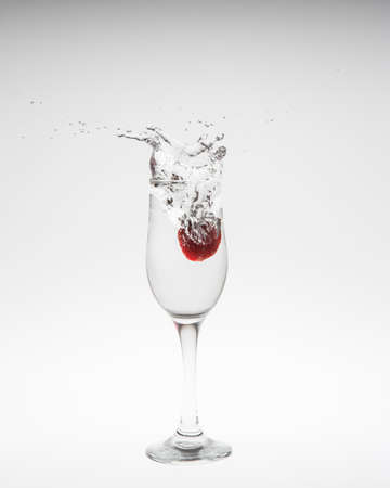 Close-up image of strawberry dropped to water on white backgroundの写真素材