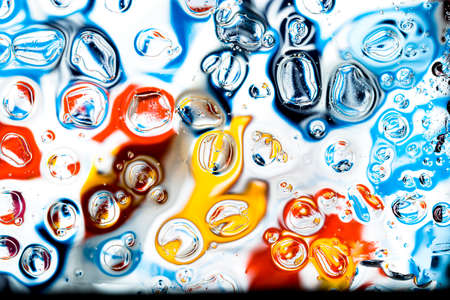 Oil and water droplets on a colorful background.の写真素材