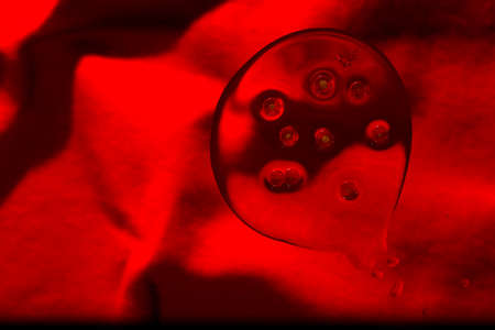 Oil and water droplets on red  background.