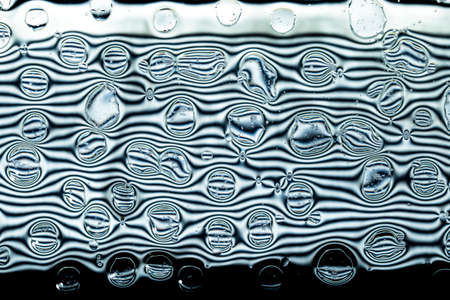 Oil and water droplets on a black and white background.