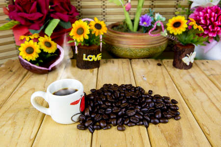 A cup of coffee costs on a wooden table. next to a cup of coffee beans. creativeの写真素材