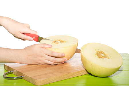 Cantaloupe is being cut on a cutting board on a white background.の写真素材