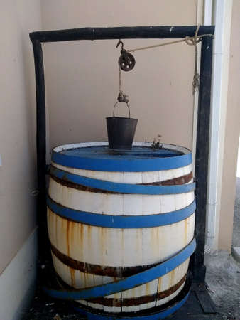 Antique painted wooden barrel-well with an old bucket in the courtyard of a rural houseの写真素材