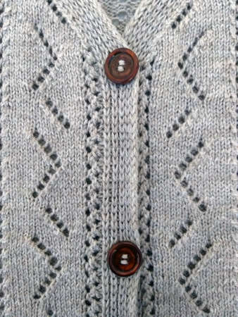 Background texture for knitting design, gray openwork cardigan with wooden buttons, knitted by handの写真素材