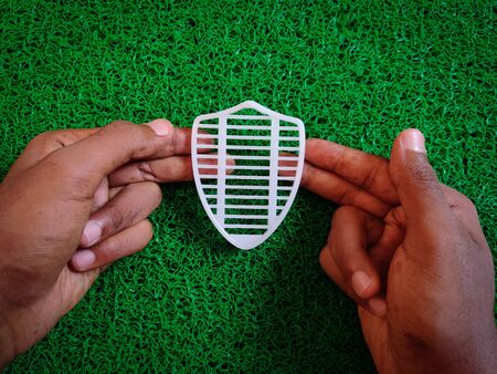 Man holding white shield in his hand. Isolated on green background. Medical concept