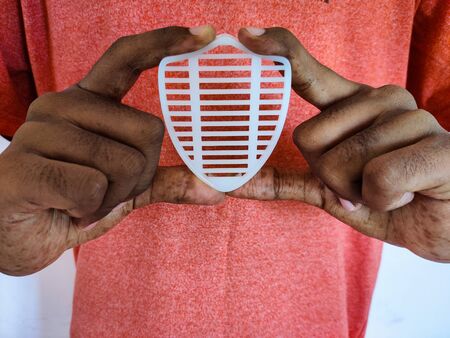 Indian man holding white shield in his hand. Isolated on pink background. Daylight. Medical concept