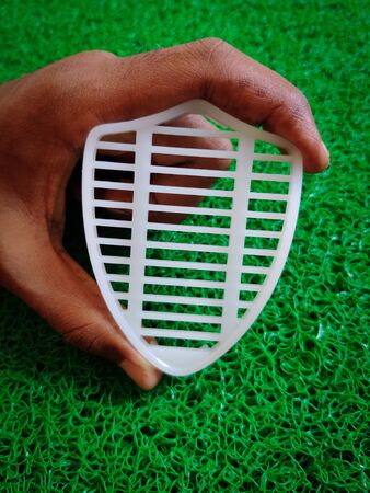 Man holding white shield in his hand. Isolated on green background. Medical conceptの写真素材