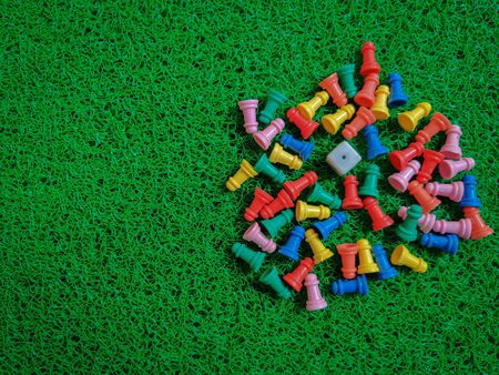 Bunch of colorful game board pieces isolated on green background. Daylightの写真素材