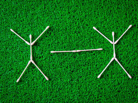 Top view of cotton ear sticks arranged as two human beings with white line represent social distance of coronavirus or covid-19 issue. Social distancing concept. Green backgroundの写真素材
