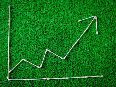 Cotton ear sticks arranged as a Increase and decrease graph on green background. Business conceptの写真素材
