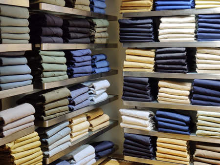 Large assortment of jeans trousers arranged on the shelf of a clothing storeの写真素材