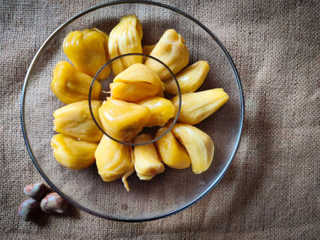 Fresh sweet jackfruit slices on a glass plate. Isolated on gunny sack