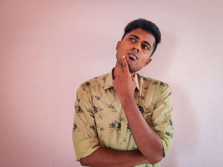 Portrait of clean shaved young South Indian man with thinking face expression