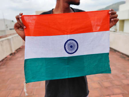 Young man holding Indian flag in his hands. Happy independence day India.の写真素材