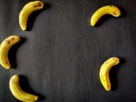Five bananas isolated on black background. Copy space in center.の写真素材