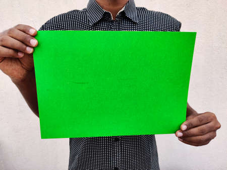 Young man in black shirt holding a blank green color chart or board or paper. Isolated on white...