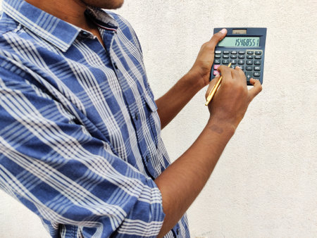 South Indian man pointing the calculator using pen. Calculating his profits White background.の写真素材