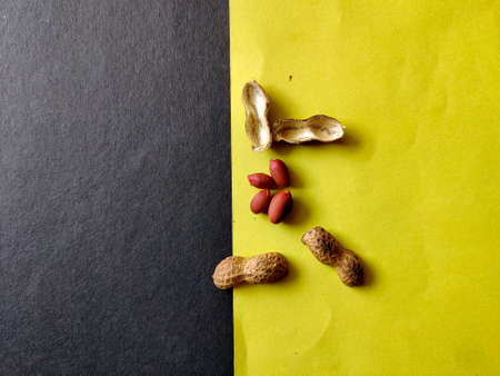 Peeled red nuts and its shell. Isolated on yellow and black background.