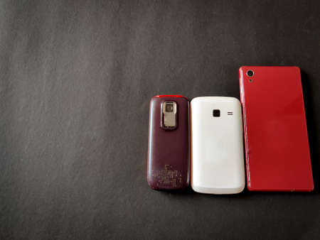 Backside of three mobile phones in different sizes.Isolated on black background. Selective focus