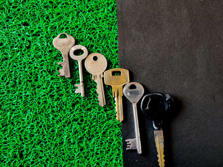 Set of keys in different sizes which includes house keys and bike key isolated on black and green...