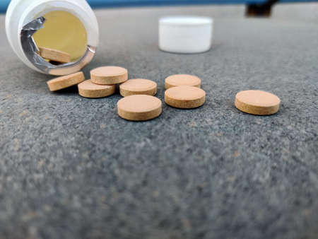 Closeup of Pill bottle with orange pills on stone background. Selective focusの写真素材