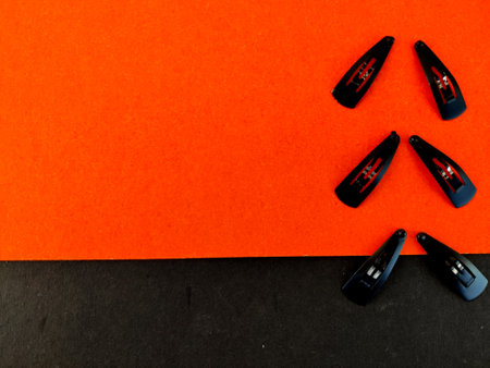 Three set of Small black color hair clips isolated on orange and black backgroundの写真素材