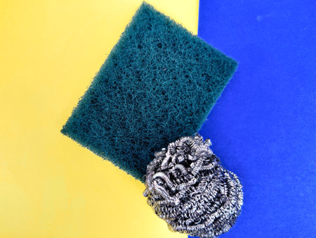 Scrubber pad and stainless steel sponge isolated on yellow and blue background.の写真素材