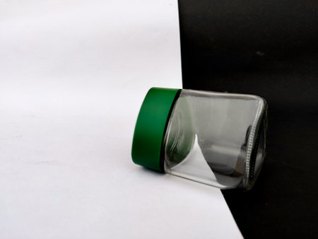 Small cute glass jar with green cap isolated on black and white backgroundの写真素材
