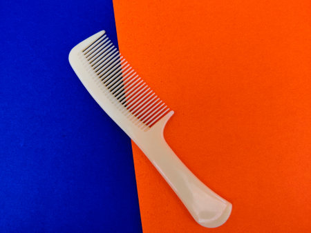 Gold comb with handle isolated on blue and orange backgroundの写真素材