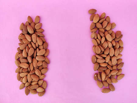 Heap of Almonds separated with copy space in center. Isolated on pink background.の写真素材