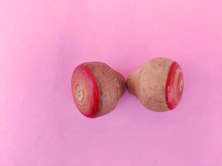 Top view of two small wooden spinning top toys isolated on pink backgroundの写真素材