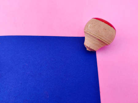 Copy space of small wooden spinning top isolated on blue and pink background