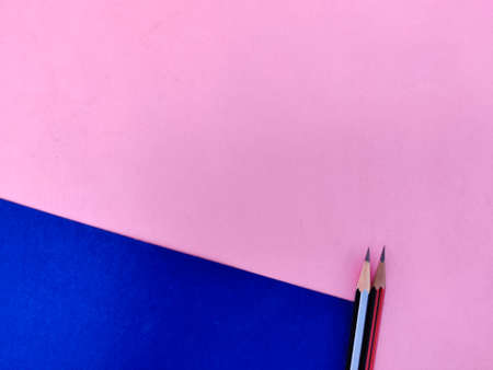 Copy space of two sharp pencils in black and red color isolated on pink and blue backgroundの写真素材